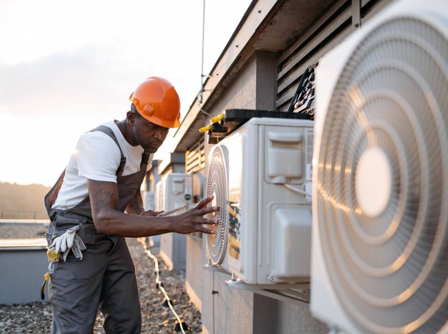 An HVAC repair technician examines an exterior unit.