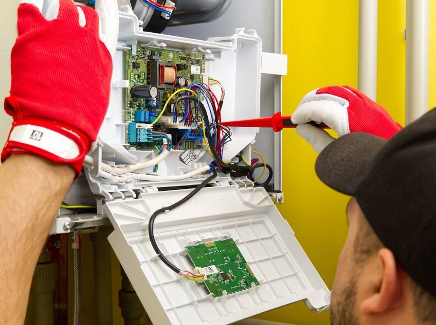 Heating repair technician taking apart a heater and removing the motherboard to diagnose system issues