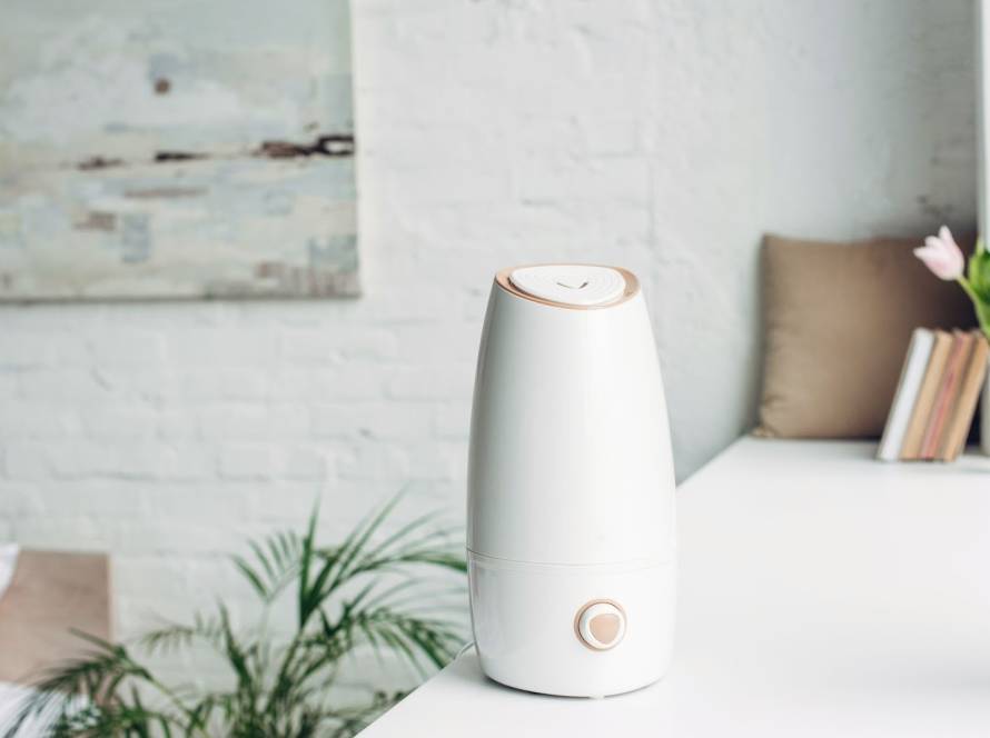 A white humidifier on a windowsill improving indoor air moisture inside a home