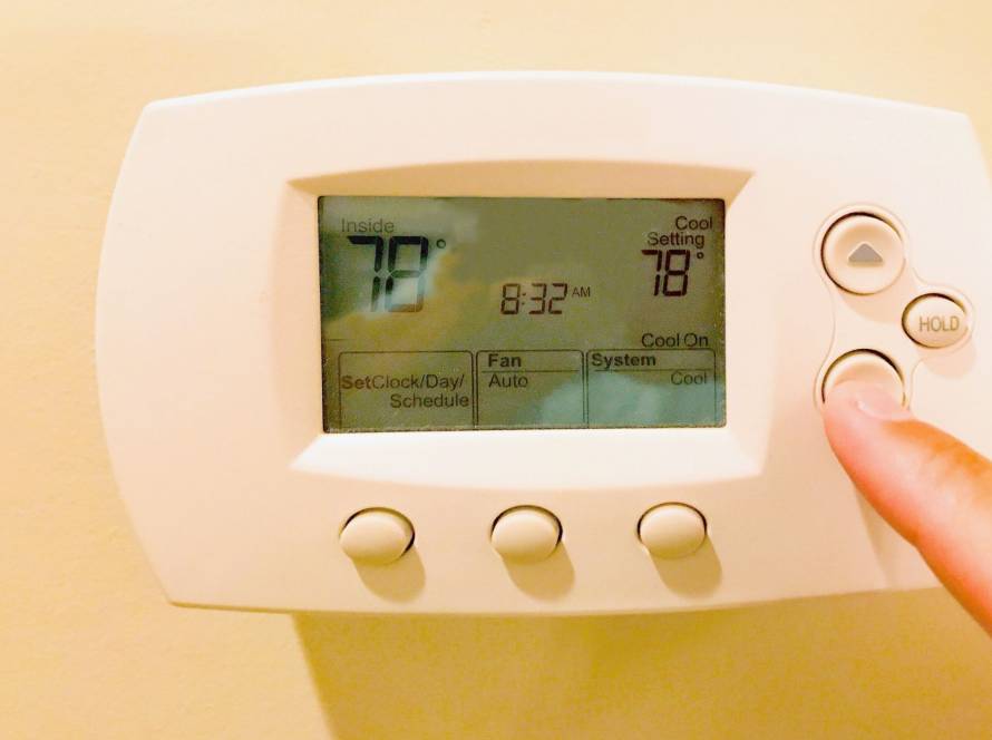 Digital thermostat display showing air conditioning temperature settings in a home